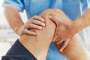 Physiotherapist doing healing treatment on patient leg. Therapist wearing blue uniform. Osteopathy, Chiropractic leg adjustment