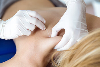 Close-up of young physiotherapist doing a trigger point injection in patient back.